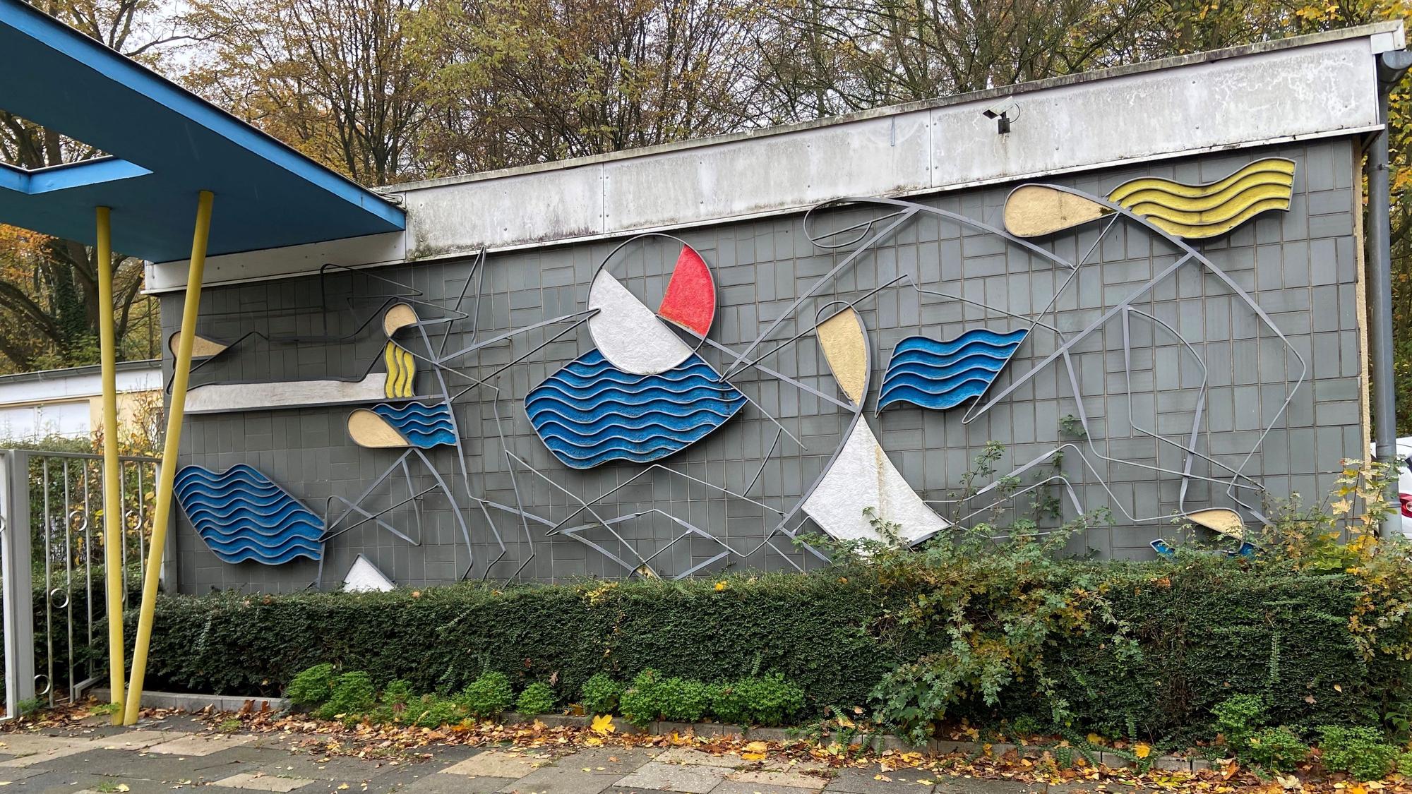 Zu sehen ist ein Wanderelief mit wellenförmigen Elementen in Blau, Rot und Gelb.