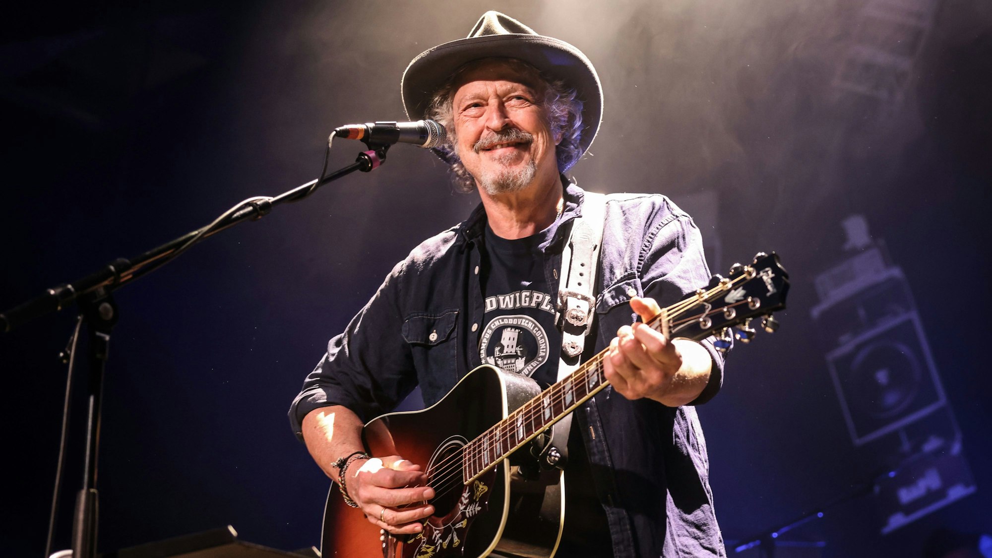 Wolfgang Niedecken steht mit einer Gitarre auf der Bühne.