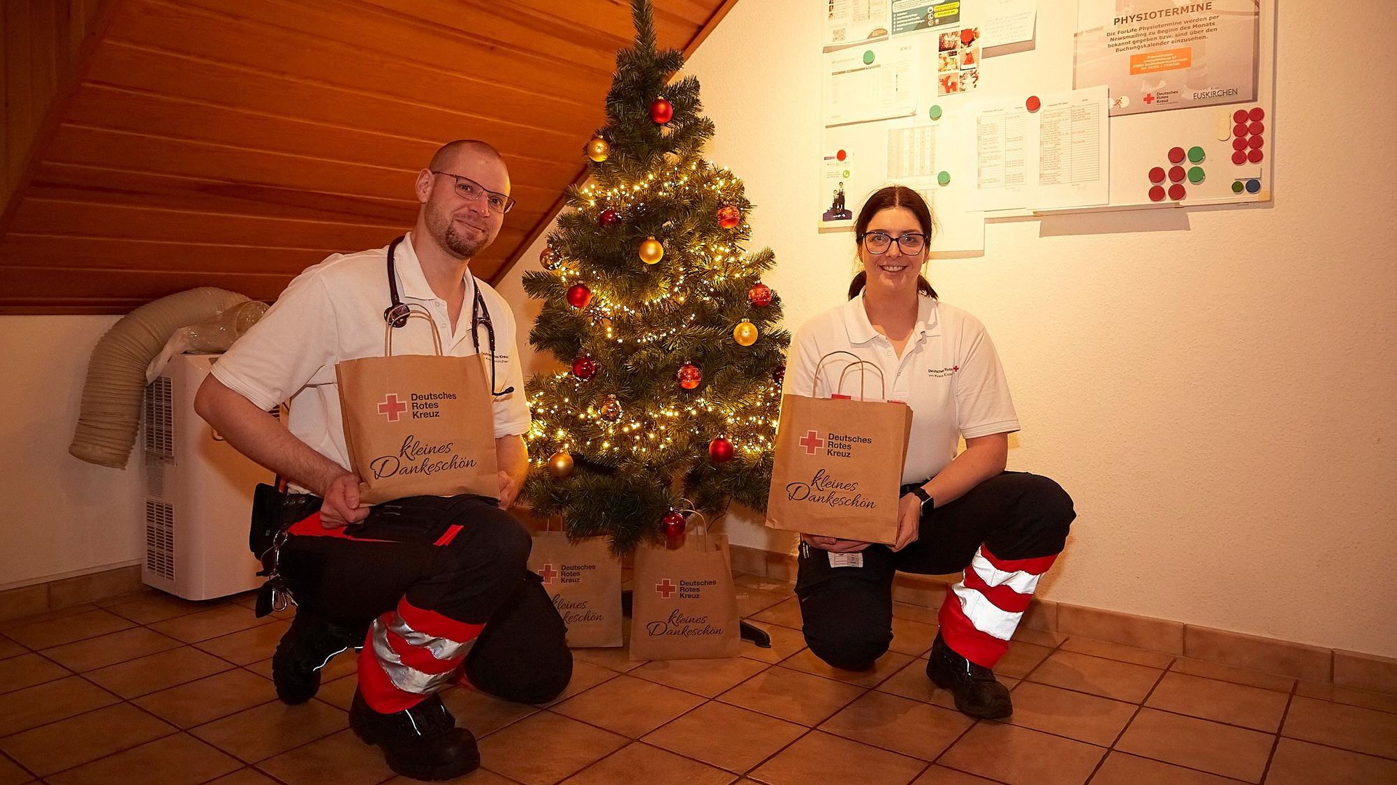 Matthias Unger und Vanessa Siebertz knien in der Rettungswache Tondorf an einem kleinen Weihnachtsbaum, mit dem sie ihre Unterkunft weihnachtlich geschmückt haben.
