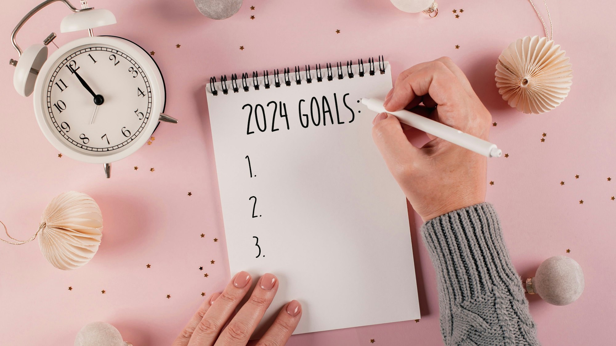 Eine Frau schreibt ihre Ziele für 2024 auf ein Blatt.