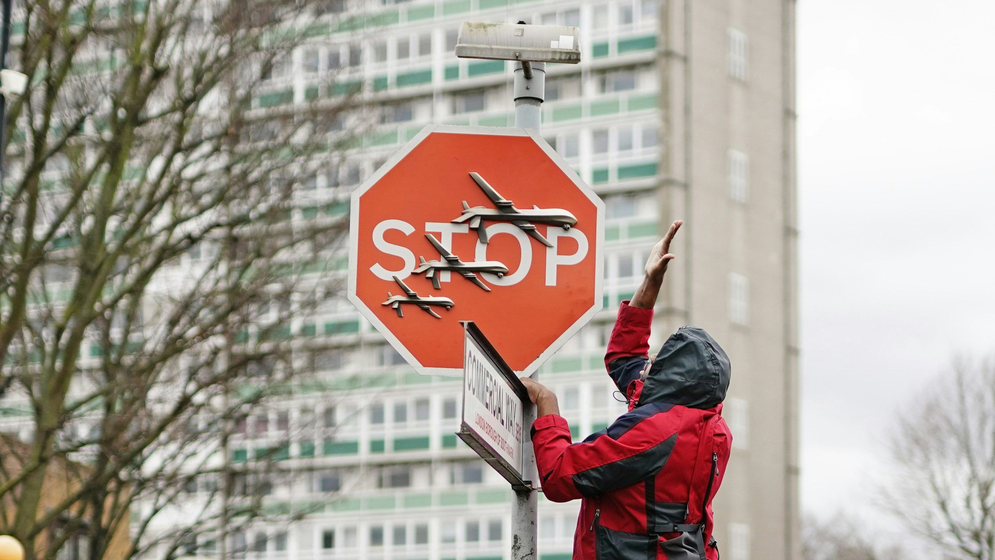 Ein Mann entfernen ein Stoppschild, auf dem drei Drohnen gemalt sind.