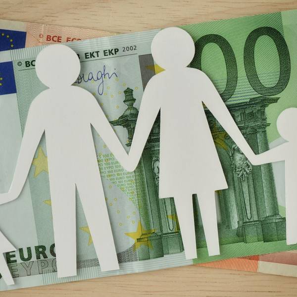 Eine Familie aus Papier ausgeschnitten liegt auf Geldscheinen.