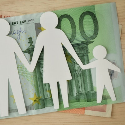 Eine Familie aus Papier ausgeschnitten liegt auf Geldscheinen.