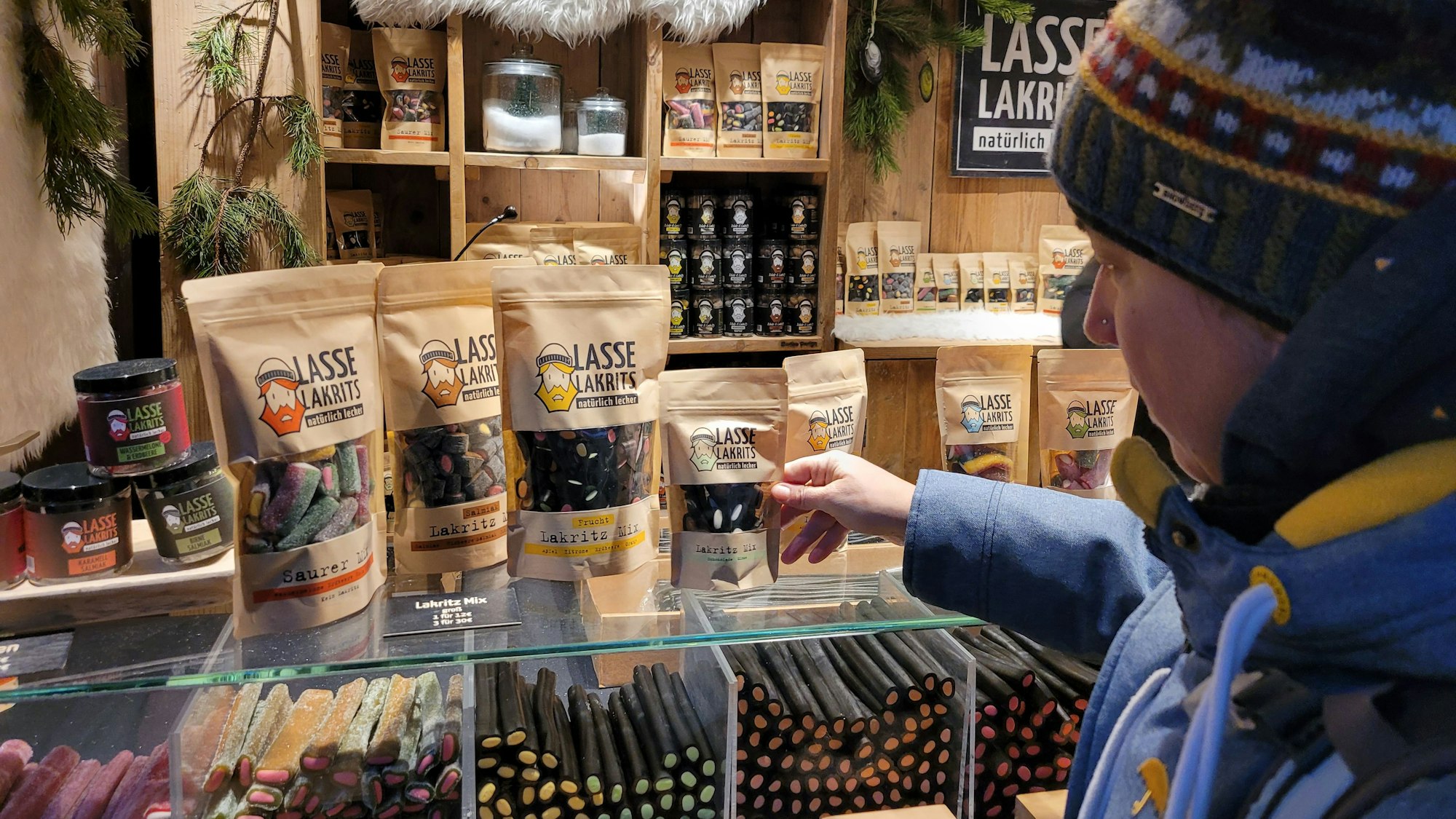 Eine Kundin schaut sich die vielen Lakritz-Produkte an, sie weiß offentsichtlich nicht, wofür sie sich entscheiden soll.