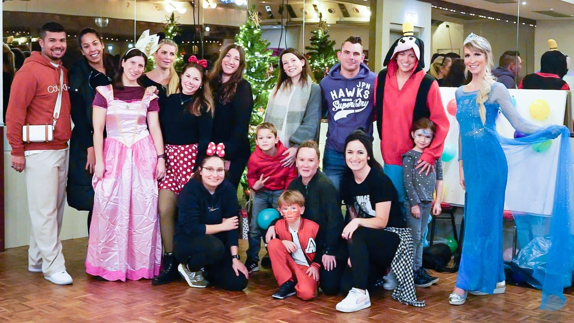 Frauen, Männer und Kinder, teils in Kostümen, posieren für ein Gruppenfoto.