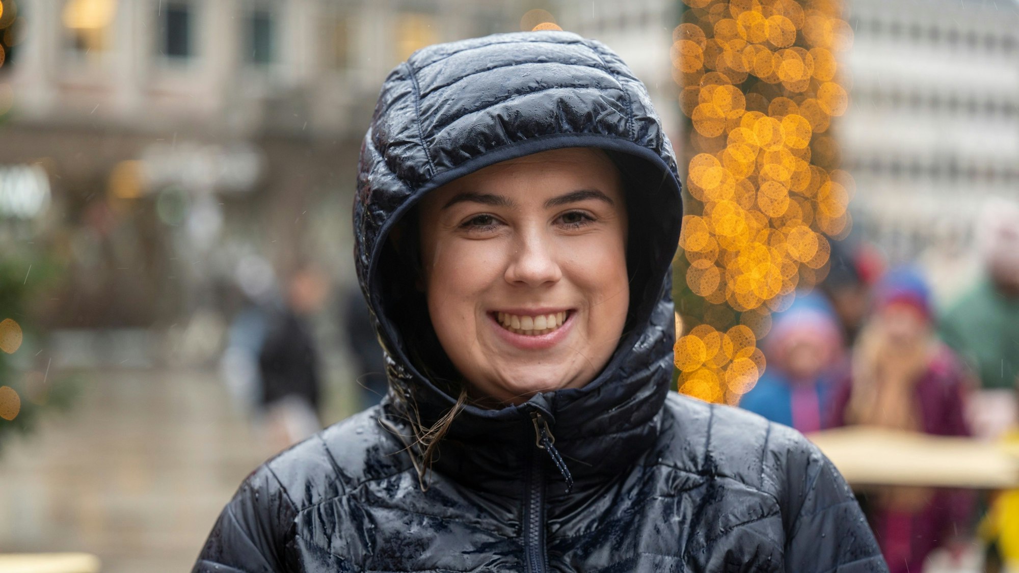 Jessica Morra trägt eine Winterjacke und hat die Kapuze auf dem Kopf.
