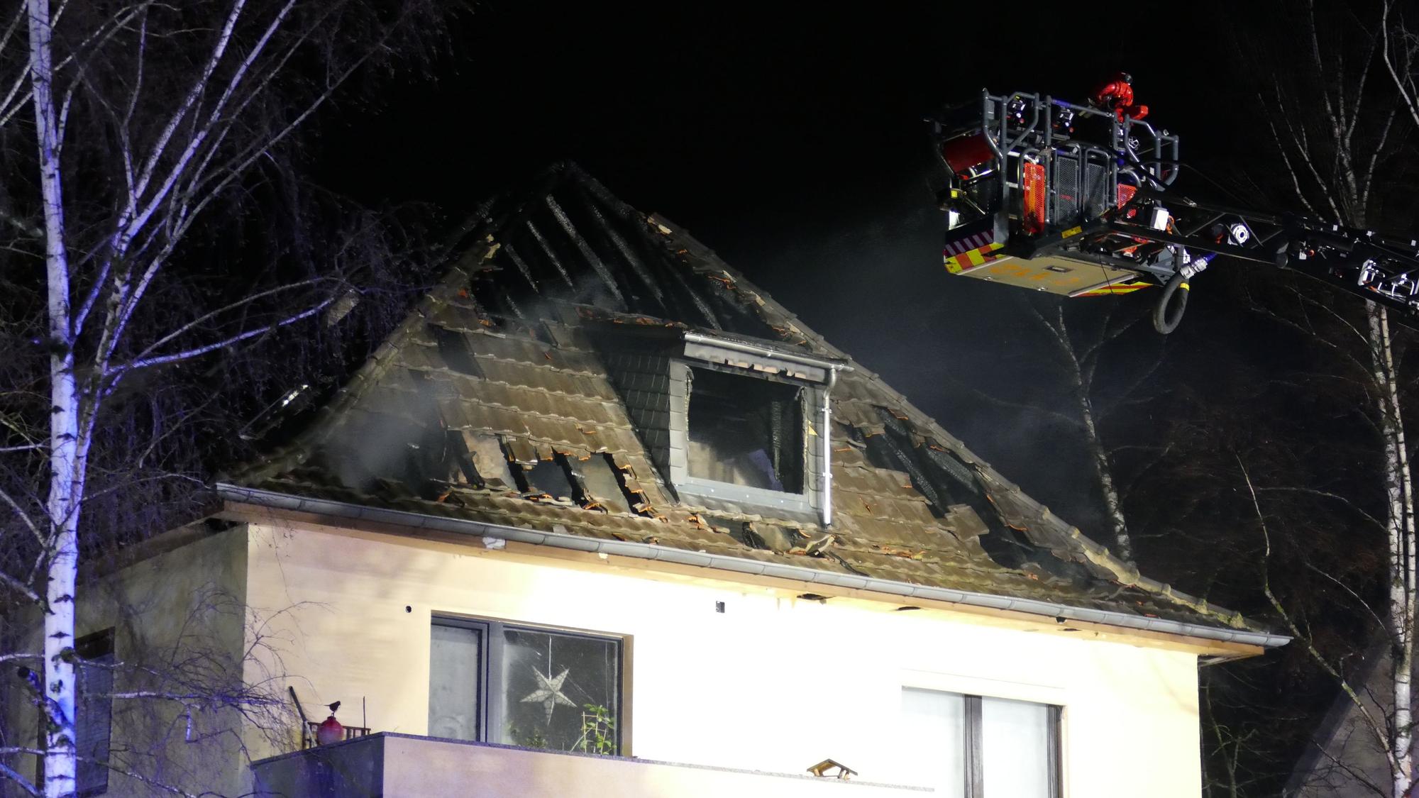 Ein Feuerwehrmann unter Atemschutz spritzt Wasser auf ein Haus.