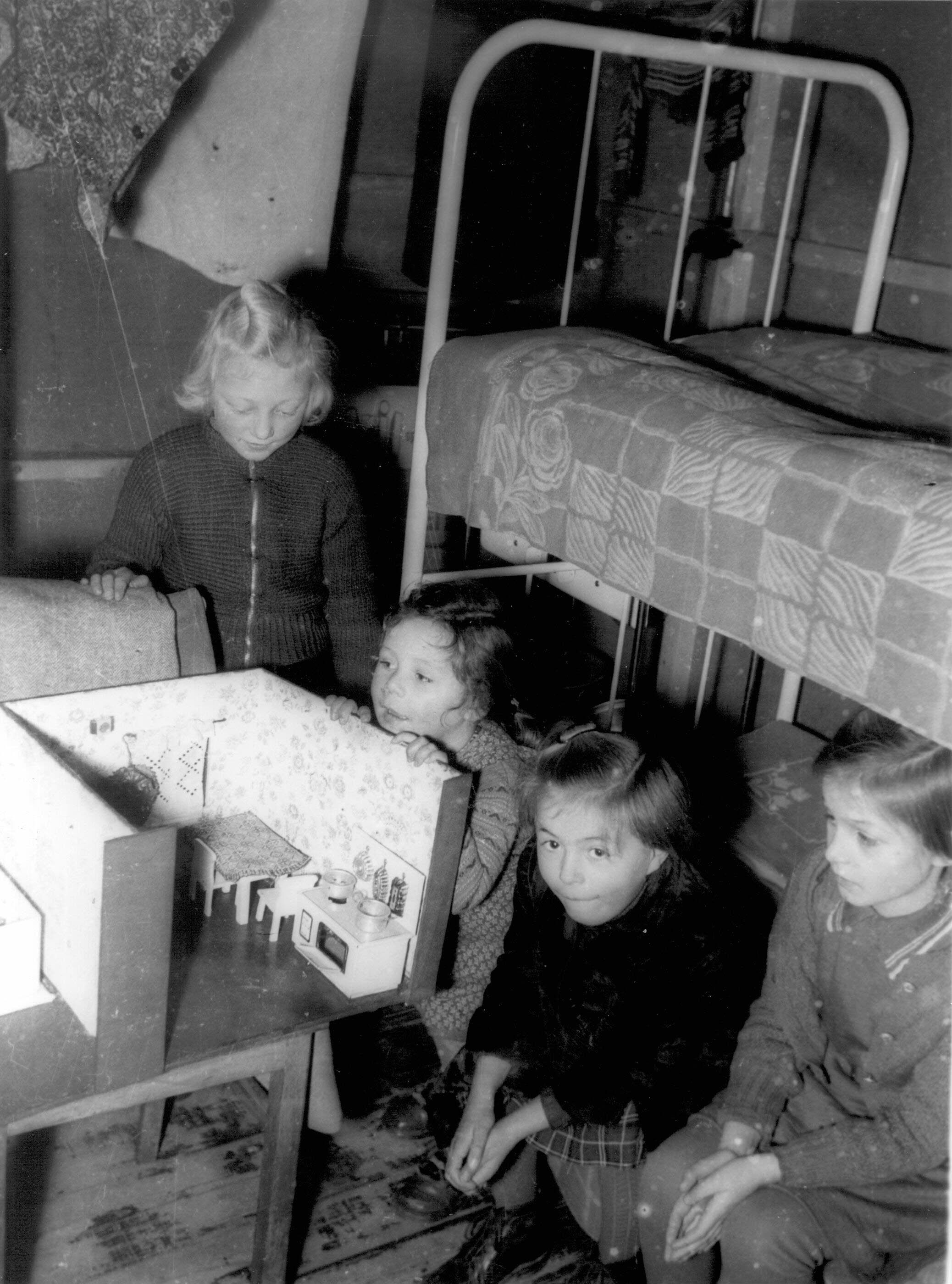 Vier kleine Mädchen freuen sich Weihnachten 1955 über ein Puppenhaus.