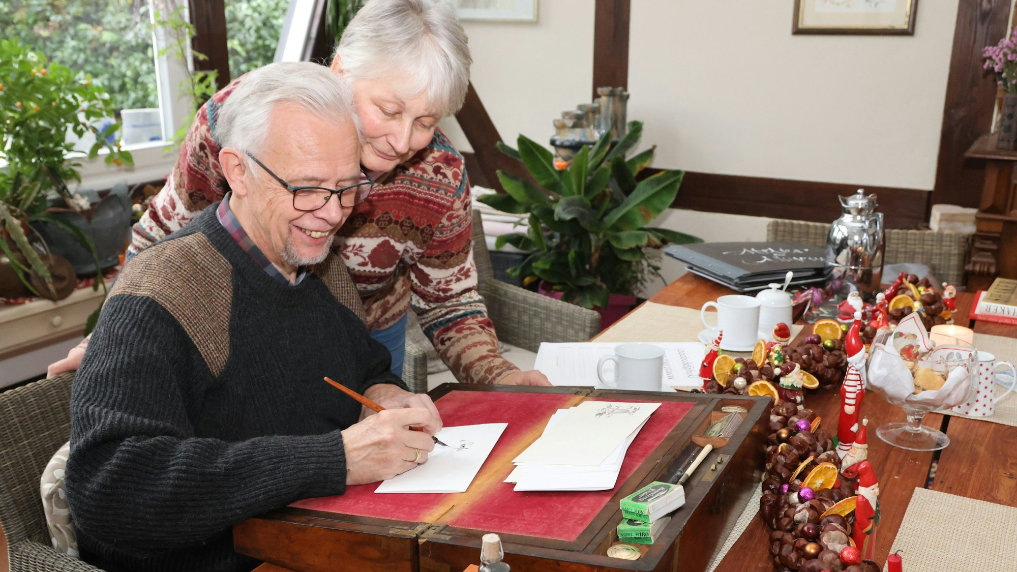 Ein Mann und eine Frau schreiben gemeinsam einen Weihnachtsbrief.