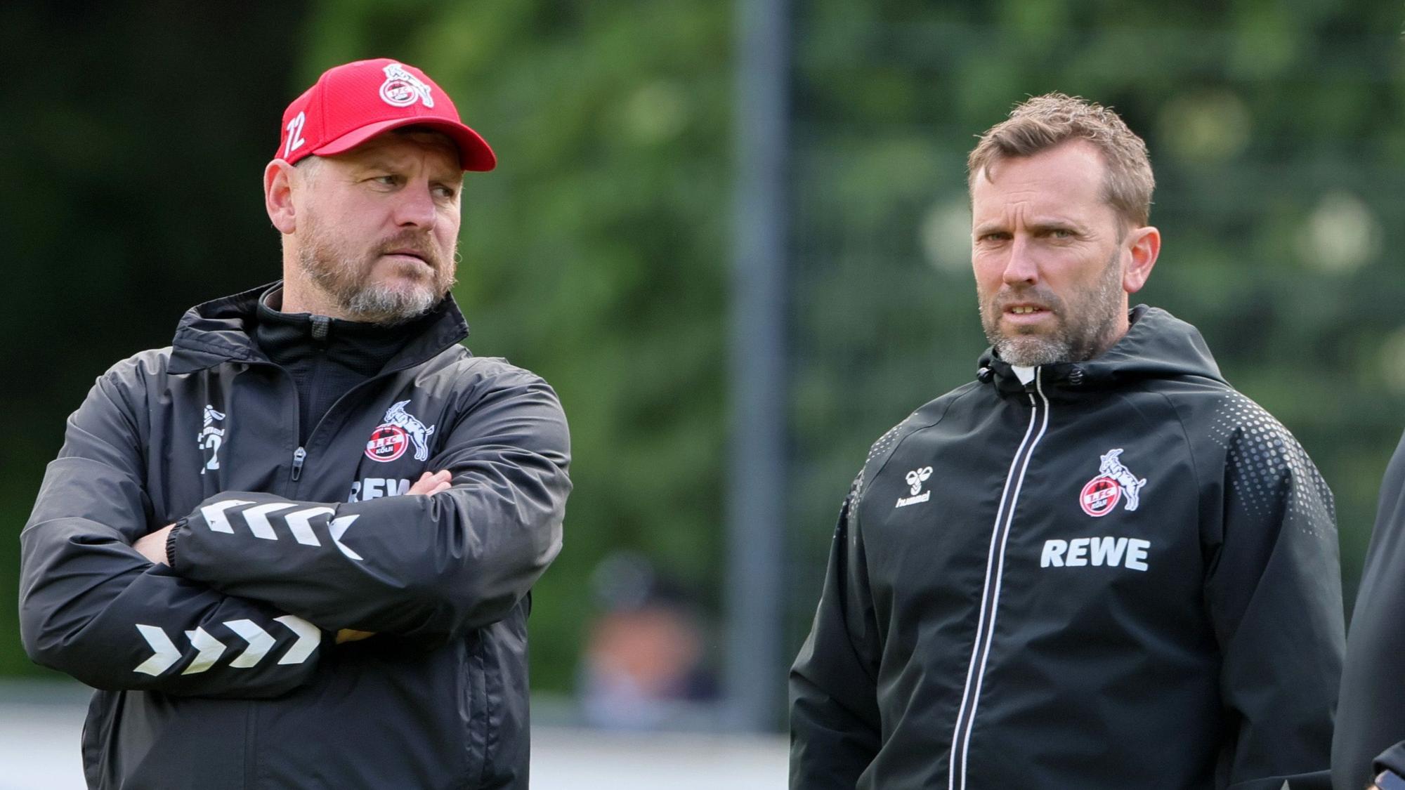 Steffen Baumgart (l.), Cheftrainer des 1. FC Köln, unterhält sich mit seinem Assistenten André Pawlak.