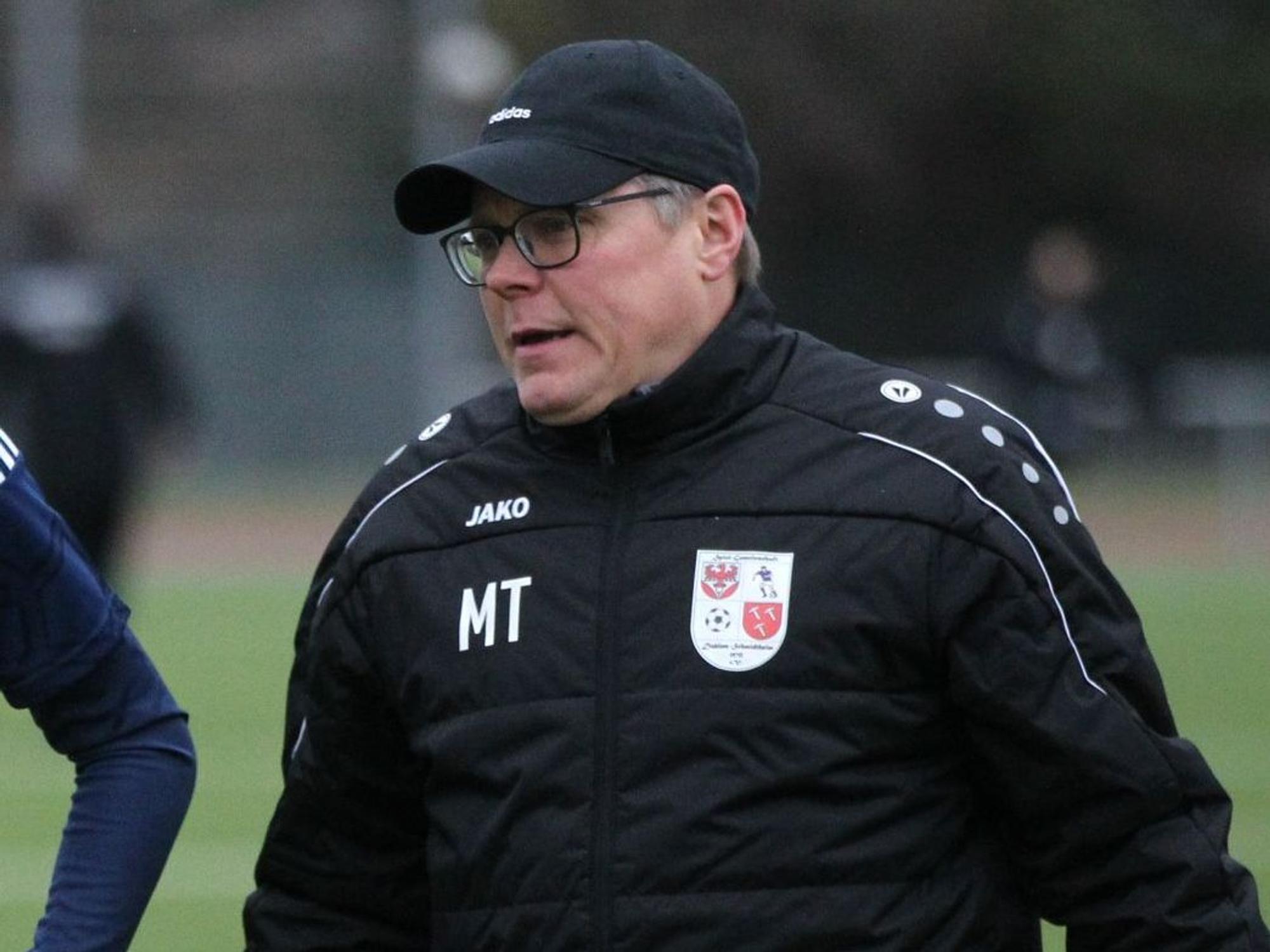Marcel Schmitt läuft in seiner Trainerjacke über den Fußballplatz.
