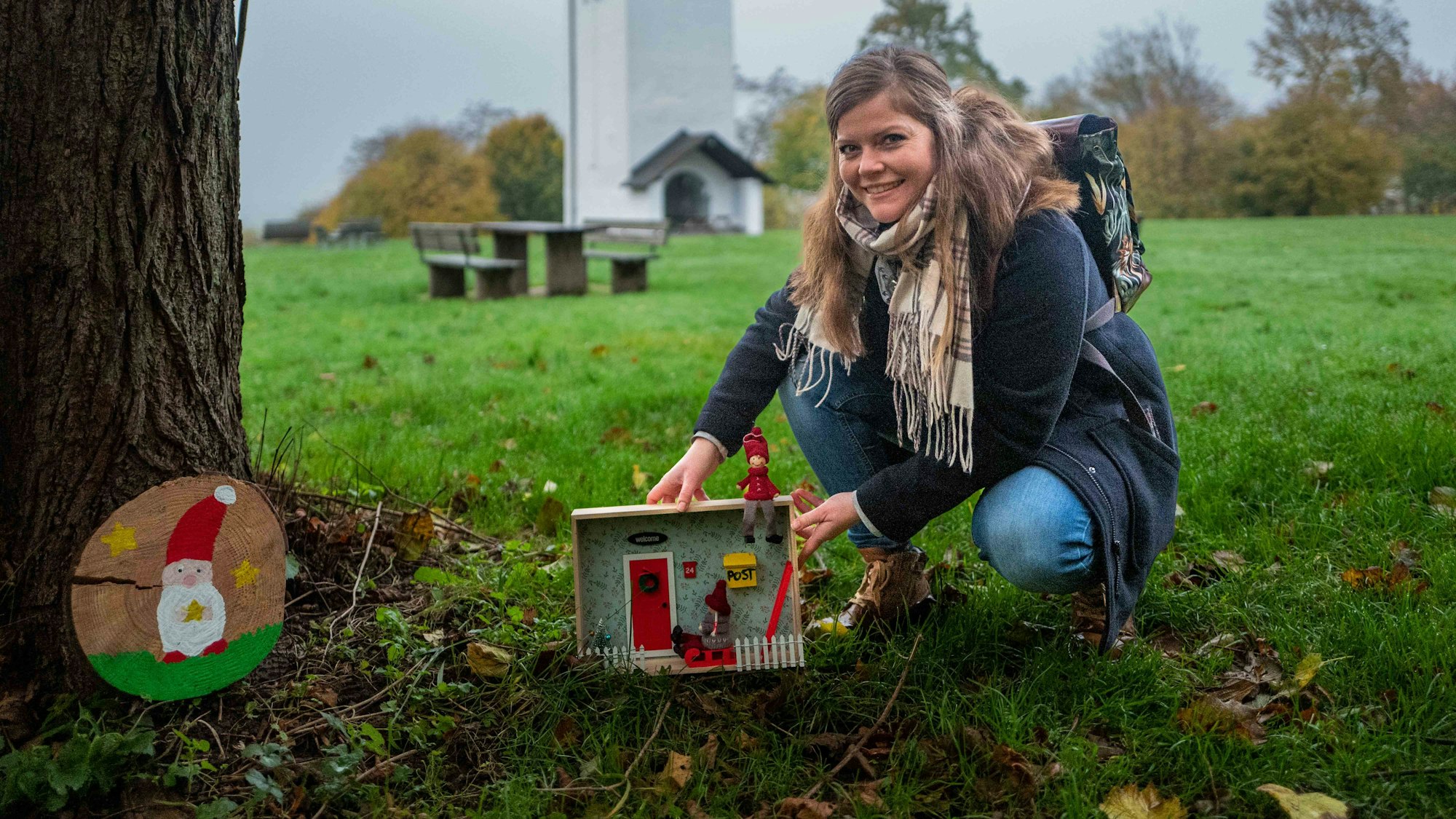 Das Bild zeigt Patricia Dreesbach vor dem Swister Turm, wie sie an einem Baum eine Wichtelwohnung aufstellt.