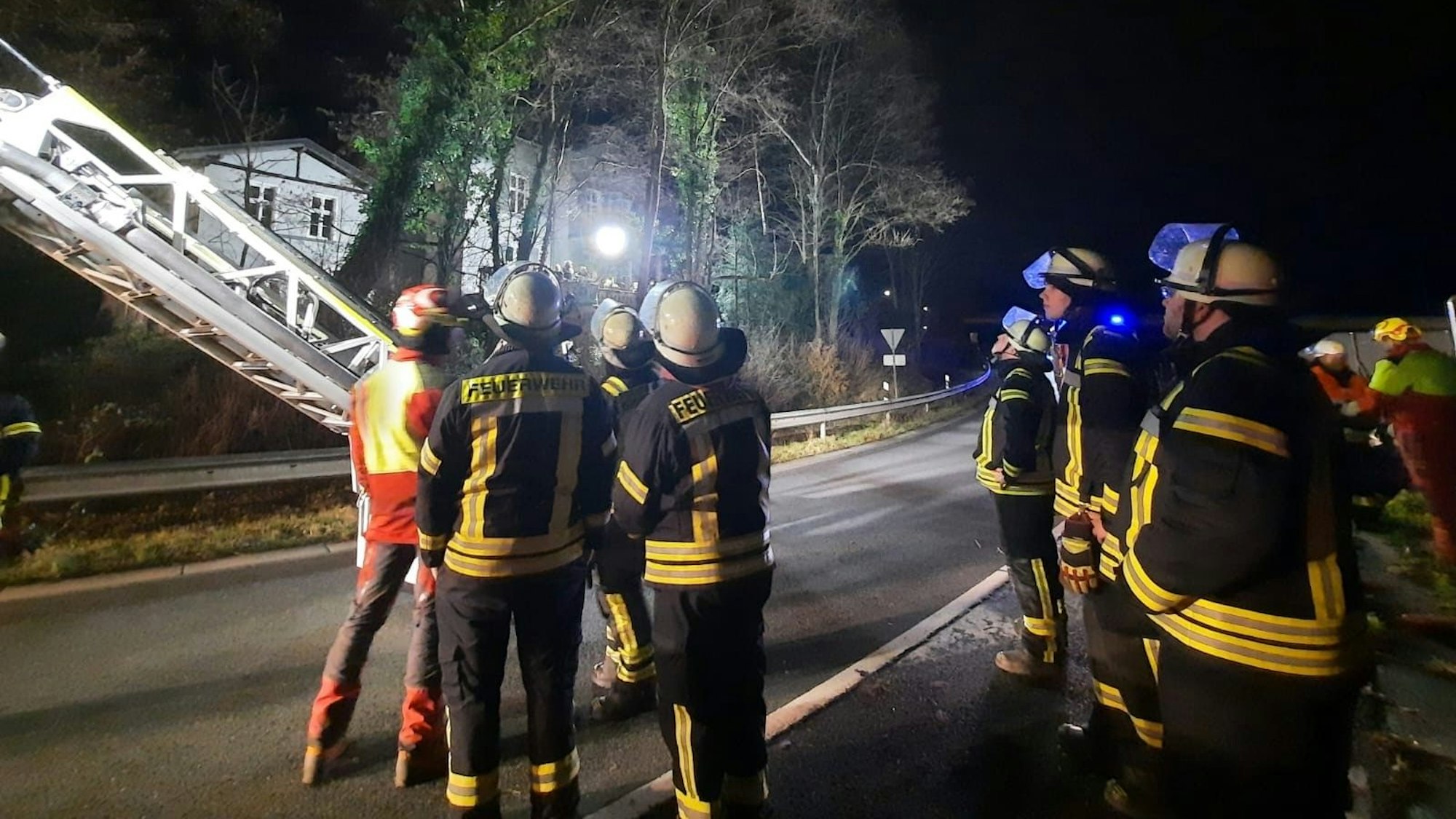 Feuerwehrleute stehen auf der Straße, eine Drehleiter ist ausgefahren.