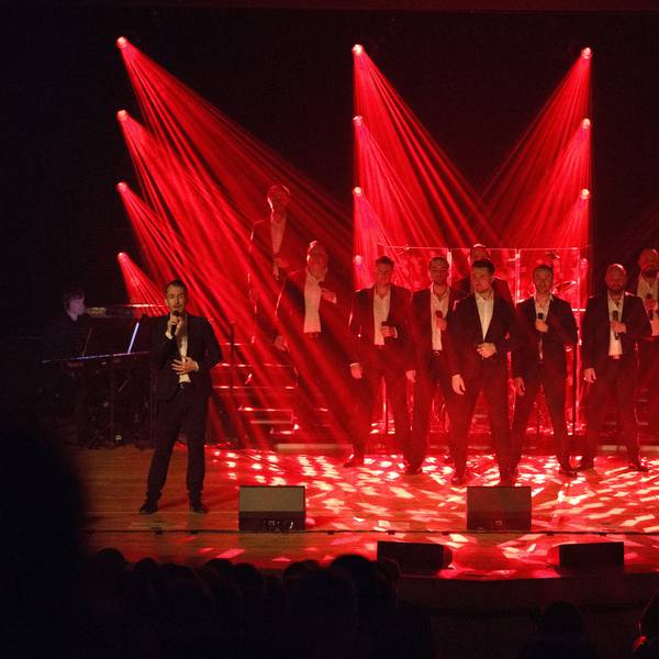 The 12 Tenors stehen auf der Bühne und werden von rot angestrahlt.