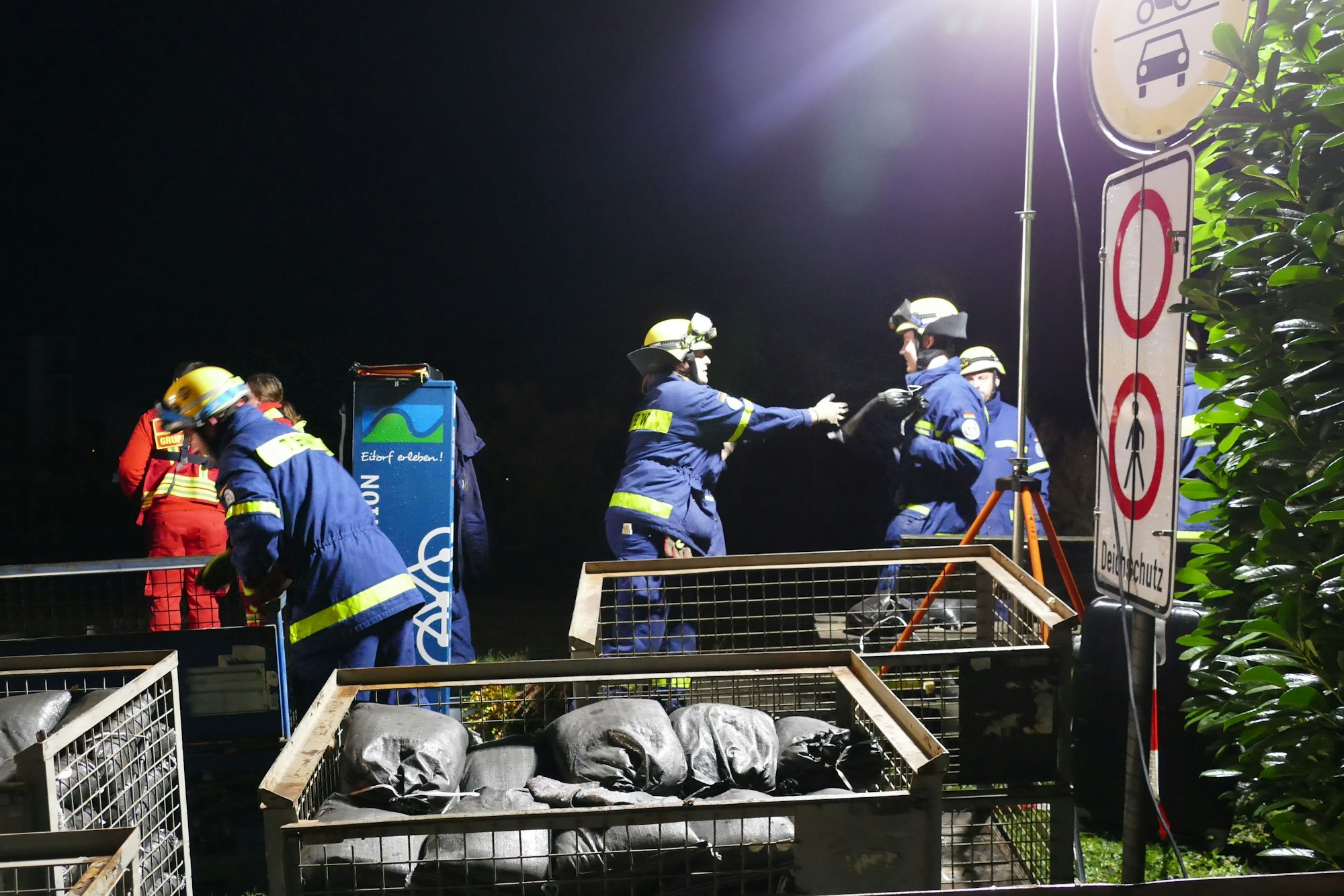 Angehörige des THW reichen Sandsäcke weiter.