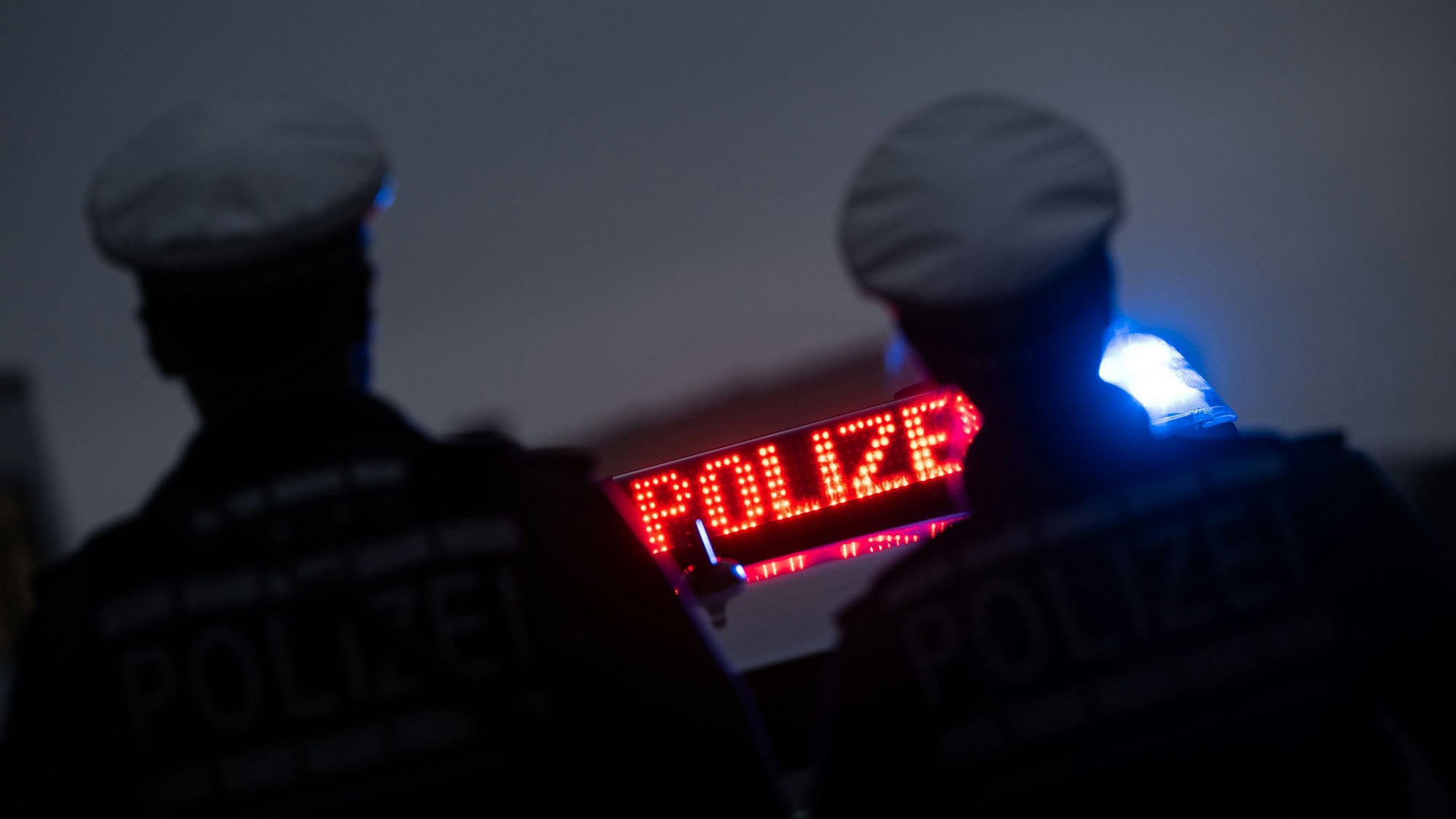 ARCHIV - 30.11.2023, Baden-Württemberg, Stuttgart: ILLUSTRATION - Zwei Polizisten stehen im Rahmen eines Fototermins vor einem Polizeifahrzeug. Die unabhängige Bundesbeauftragte für Antidiskriminierung, Ferda Ataman, hat den Reformentwurf zum Polizeigesetz als einseitig kritisiert. Foto: Marijan Murat/dpa +++ dpa-Bildfunk +++