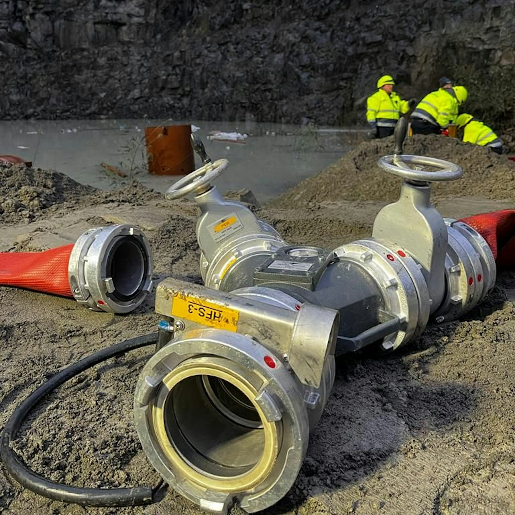 Eine Kupplung für Feuerwehrschläuche liegt neben einem gefluteten Steinbruch.