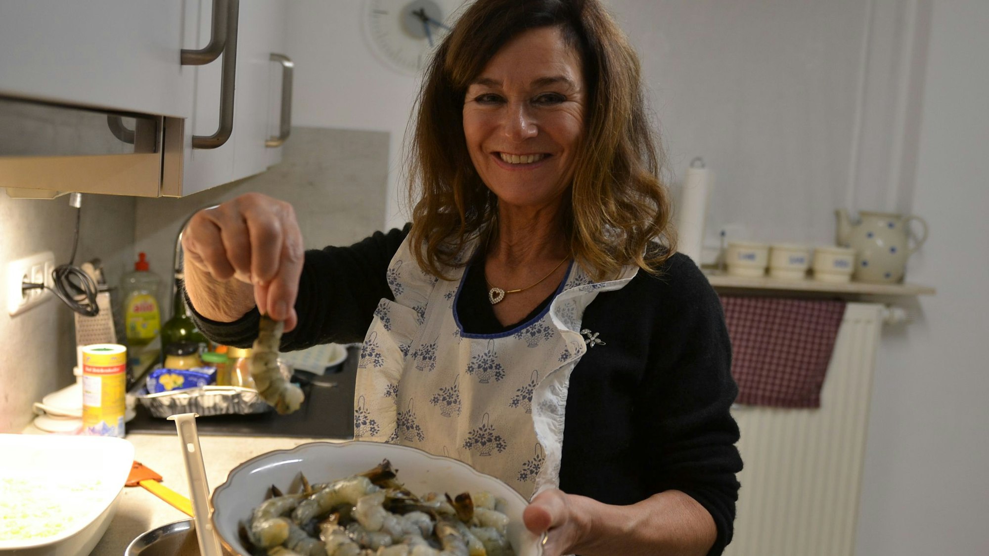 Susi Assenmacher hält einen Teller mit Garnelen in der Hand.