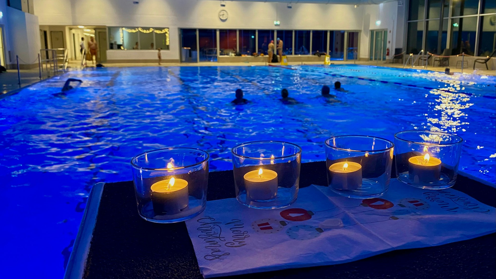 Vor einem Schwimmbecken stehen vier Kerzen.