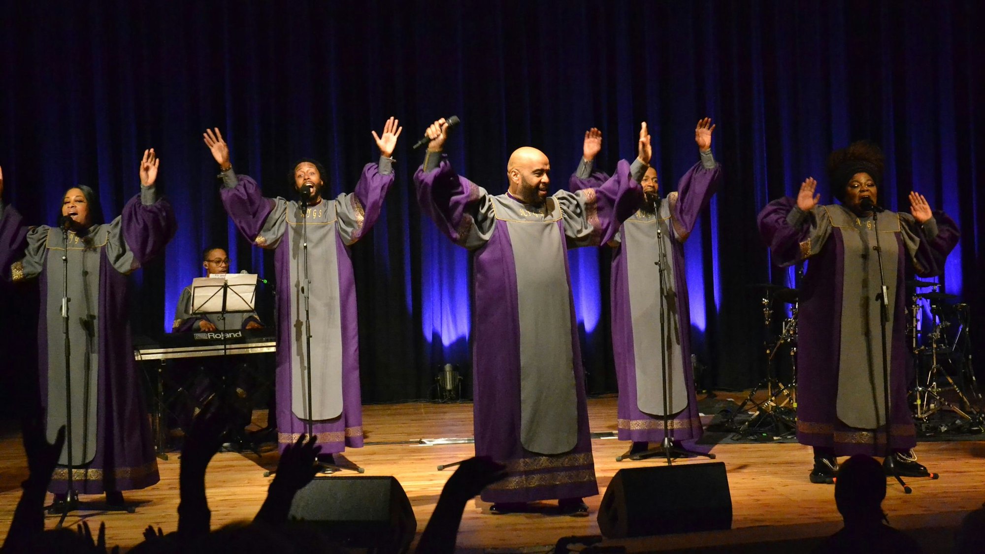 Das Ensemble der New York Gospel Stars steht mit erhobenen Armen auf der Bühne im Euskirchener Stadttheater und singt.