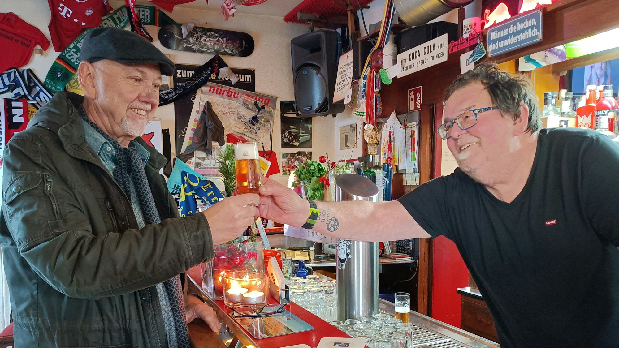 Wirt Andreas Weyrauch reicht einem Gast ein Kölsch im Pilsglas.