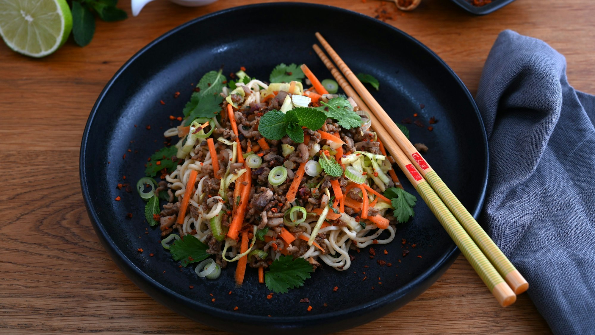 Der Salat ist auf einem Teller, auf dem ebenfalls Essstäbchen liegen.