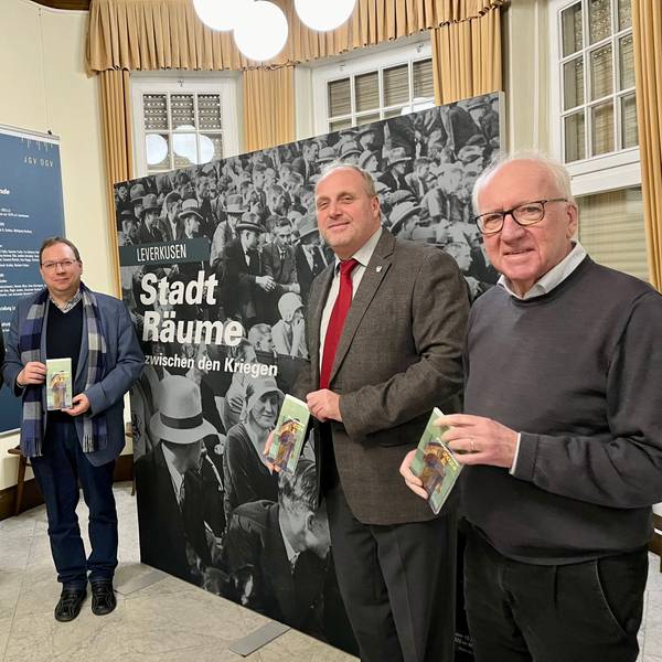 Uwe Bräutigam, Guido von Büren, Michael Gutbier und Ernst Küchler von den Geschichtsvereinen aus Opladen und Jülich vor dem Plakat für das Ausstellungsprojekt „Stadträume“ in der Villa Römer