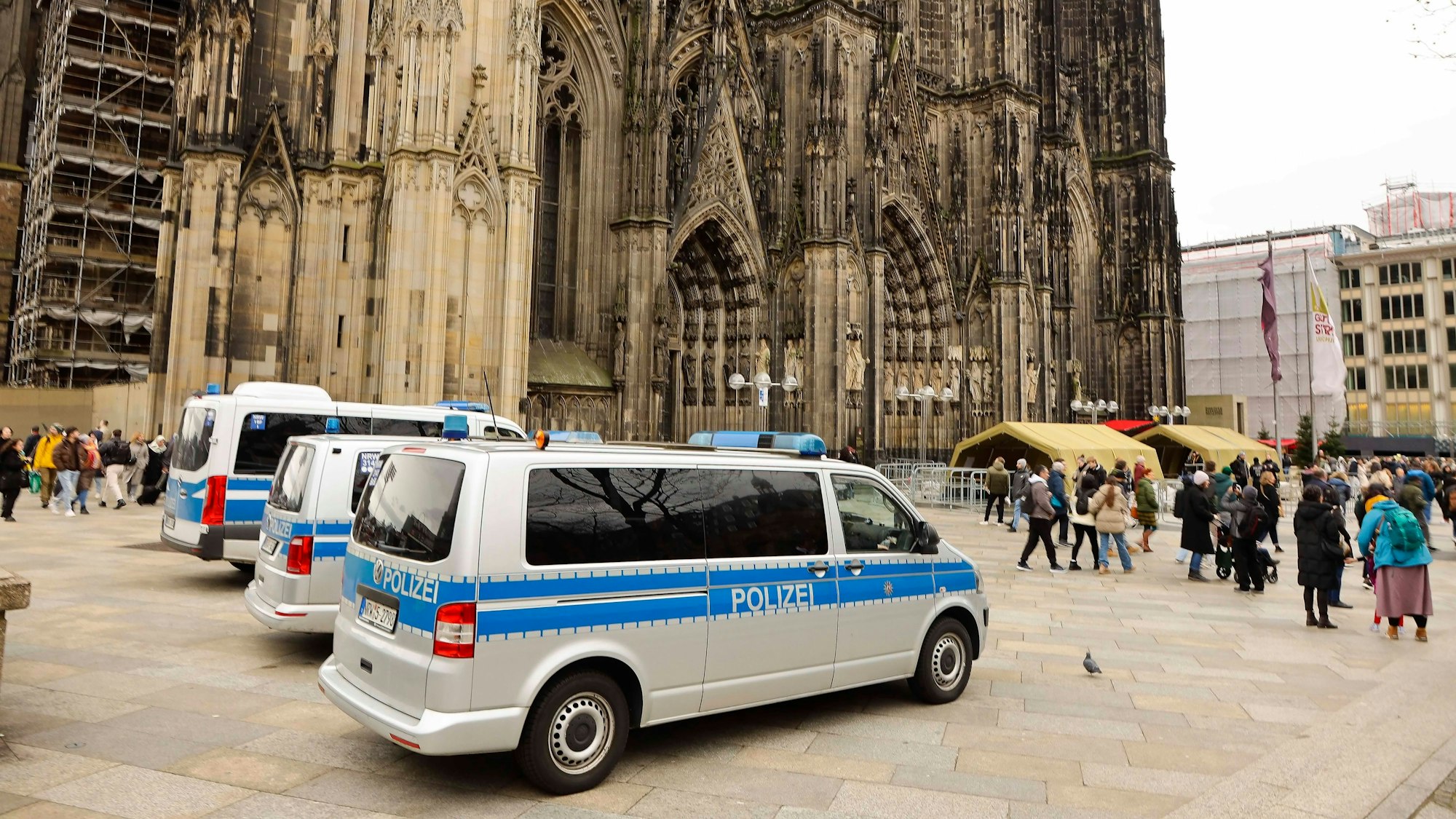 Mannschaftswagen der Polizei parken vor dem Kölner Dom.