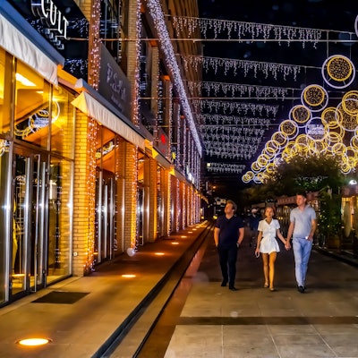 Durch die beleuchtete Fußgängerzone spazieren Passanten