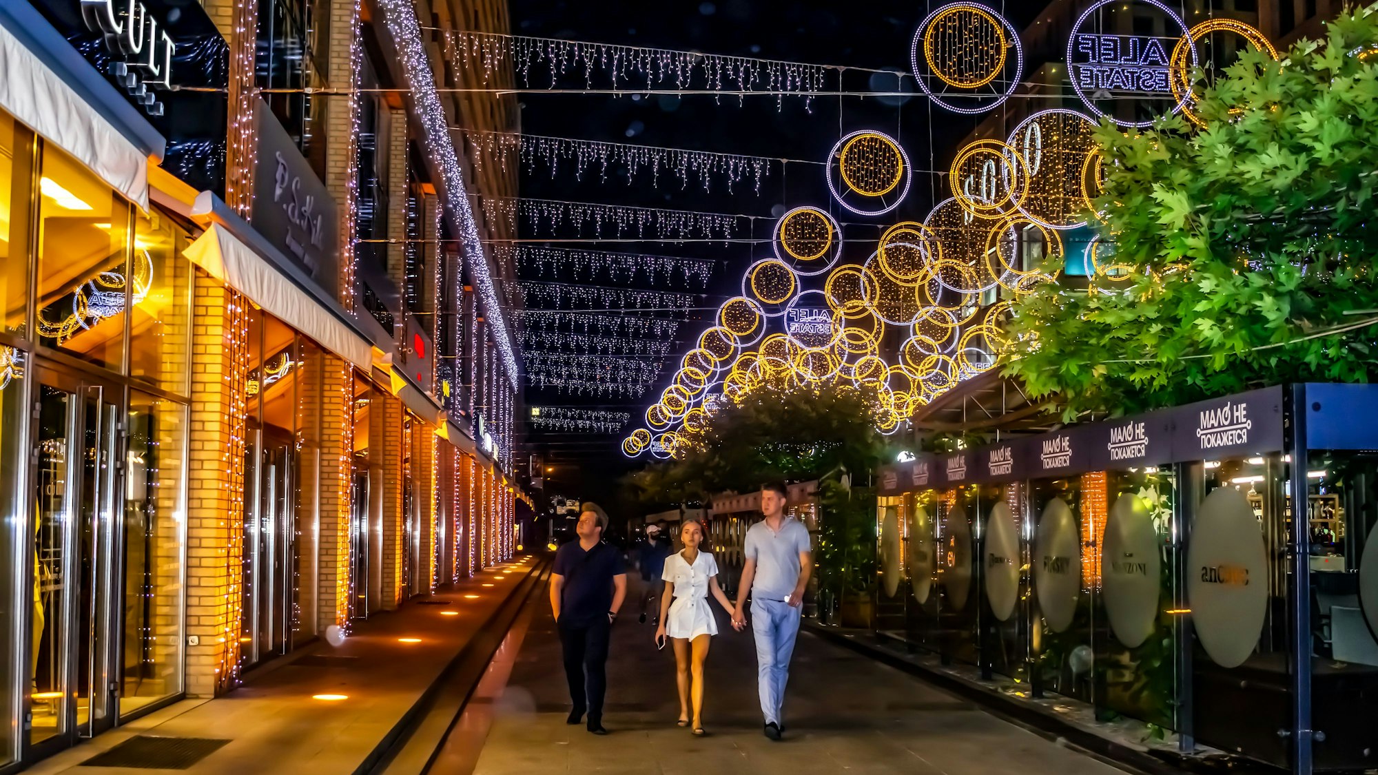 Durch die beleuchtete Fußgängerzone spazieren Passanten