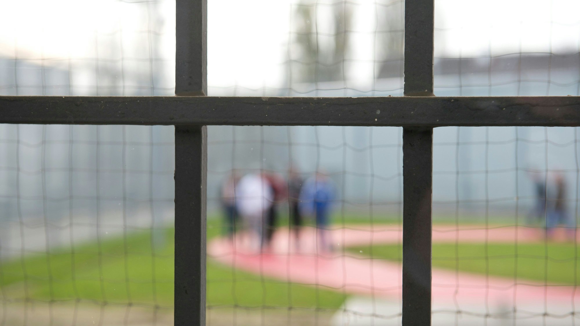 Hinter einem Gitter laufen Gefängnisinsassen der Justizvollzugsanstalt Stuttgart-Stammheim über einen Gefängnishof.