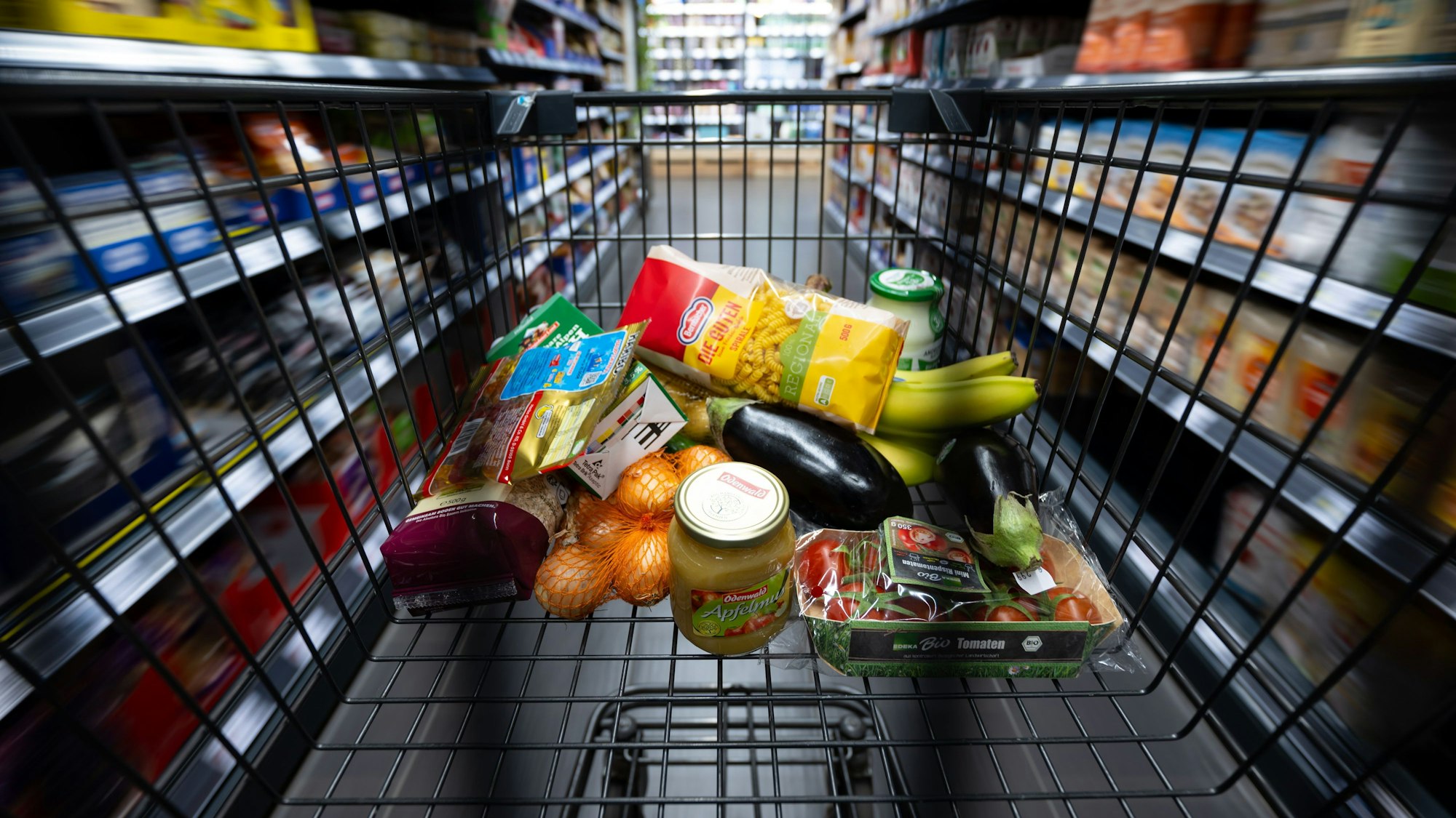 Verschiedene Lebensmittel liegen in einem Supermarkt in einem Einkaufswagen.