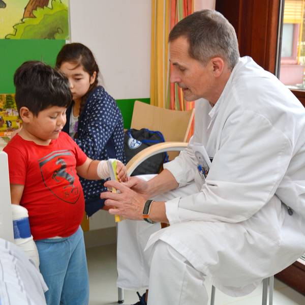 Das Foto zeigt einen Arzt und zwei Kinder