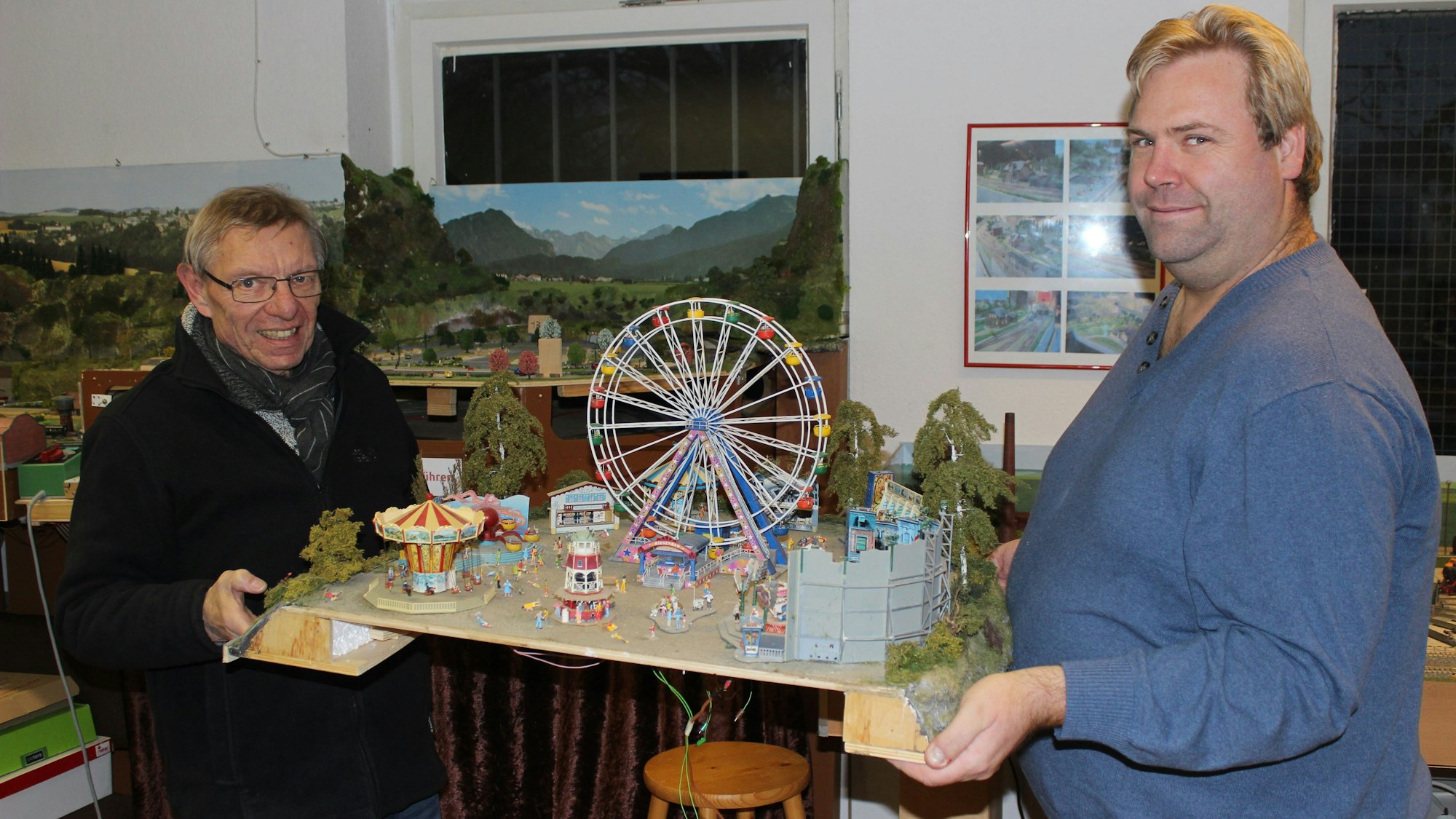 Zwei Männer halten das Modell einer Kirmes in die Kamera.