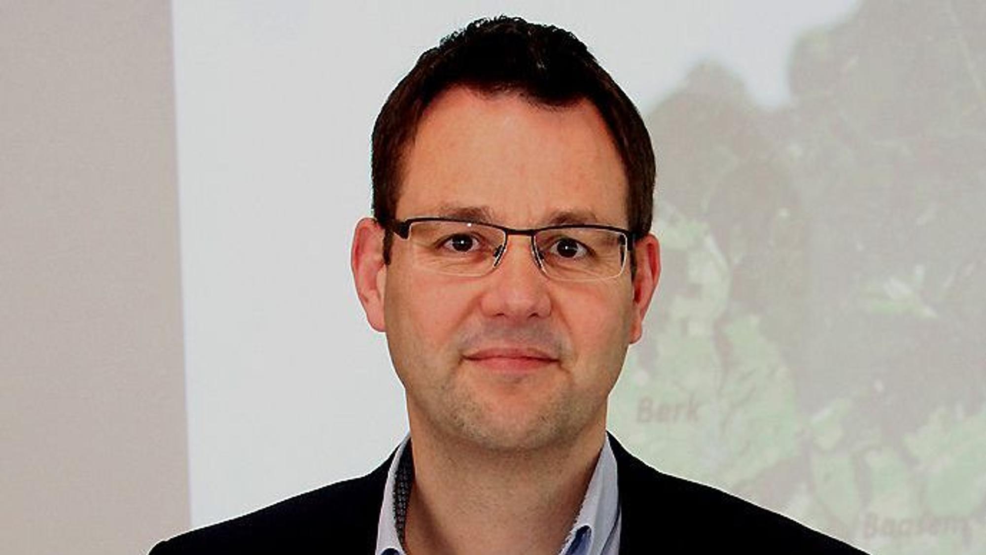 Frank Hütter, Kämmerer der Gemeinde Dahlem, steht vor einer Wand, an der per Beamer eine Karte der Gemeinde projiziert wird.