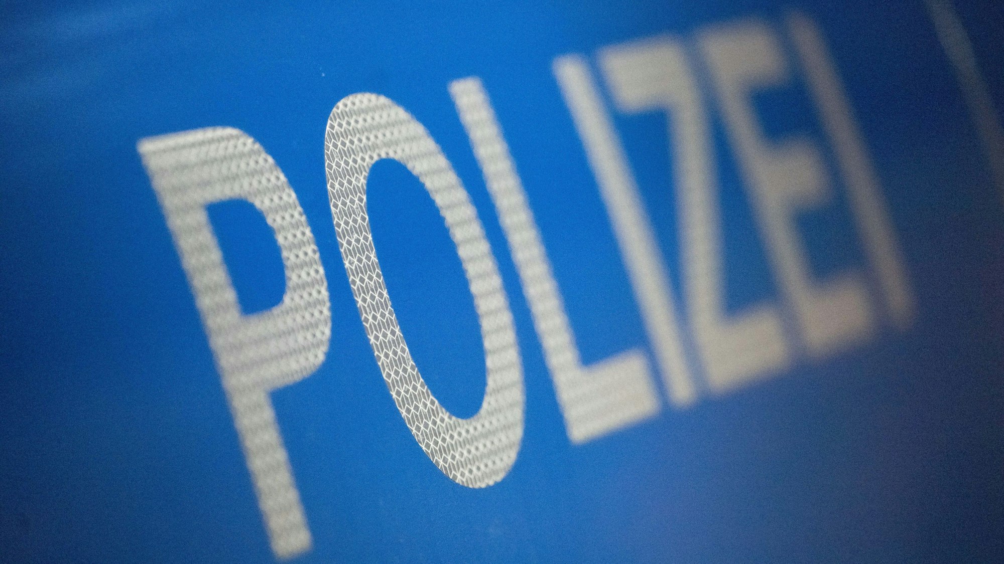 Das Wort Polizei ist im Rahmen eines Fototermins auf der Karosserie eines Polizeifahrzeugs zu sehen.
