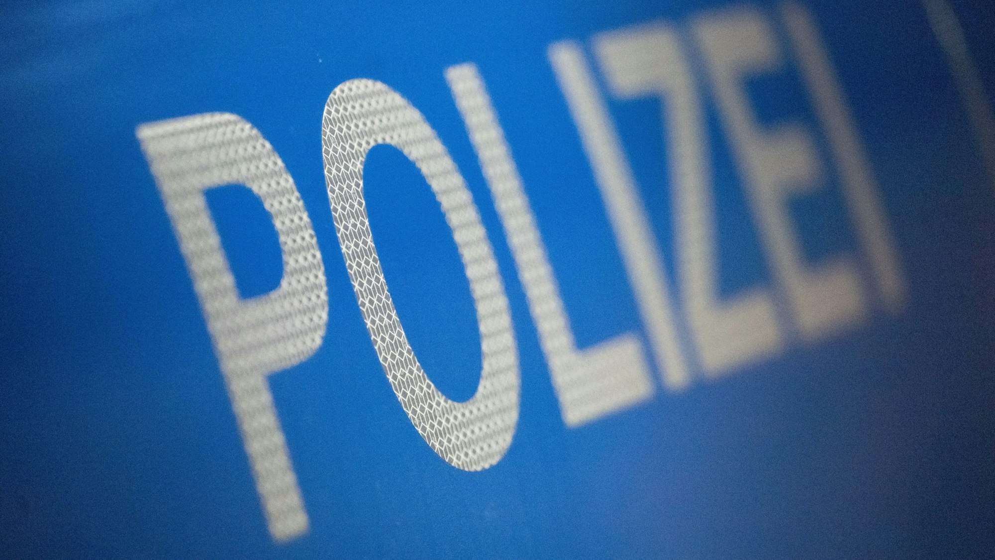 Das Wort Polizei ist im Rahmen eines Fototermins auf der Karosserie eines Polizeifahrzeugs zu sehen.