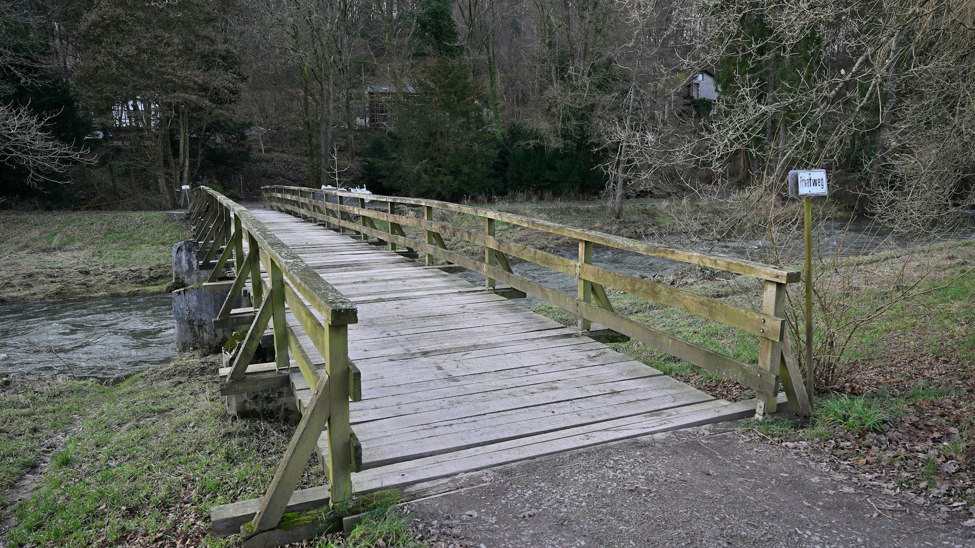 Zu sehen ist die Holzbrücke über die Sülz. Am Ufer rechts und links sind überspülte Wiesen.