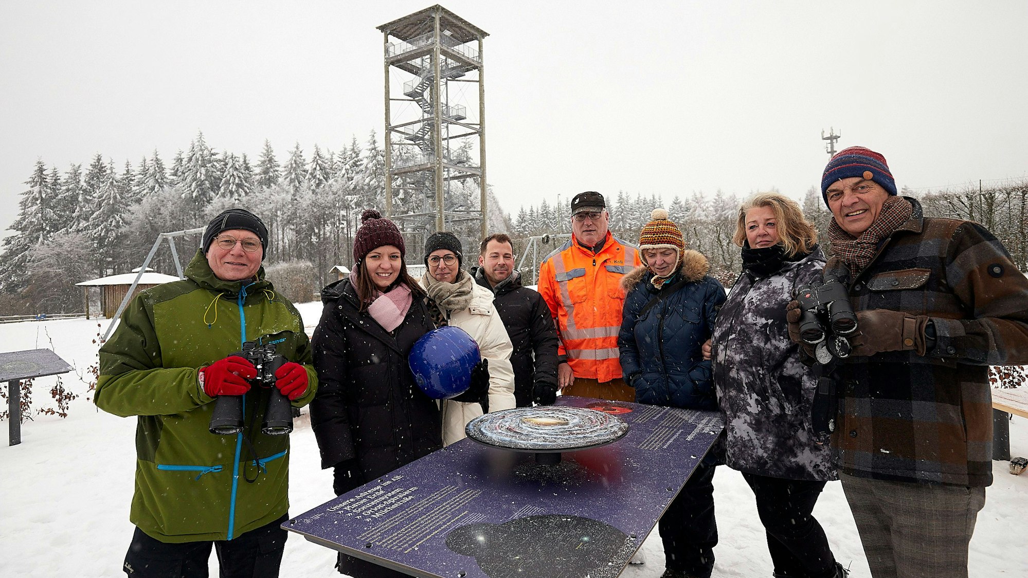 Die Vertreter der Gemeindeverwaltung, Touristiker und Gastgeber an einer der Info-Tafeln. Im Hintergrund des verschneiten Areals der Aussichtsturm am Weißen Stein.