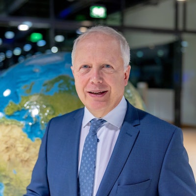 WDR-Intendant Tom Buhrow steht vor einer Weltkugel. Er trägt einen blauen Anzug und lächelt in die Kamera.