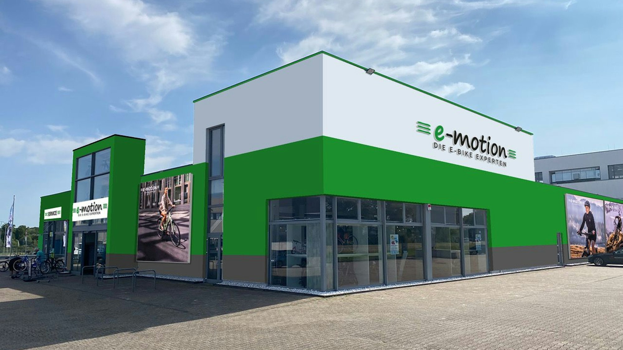 Zu sehen ist ein Gebäude mit einer grün-weißen Fassade, großen Schaufensterflächen und Fotos von Fahrradfahrern.