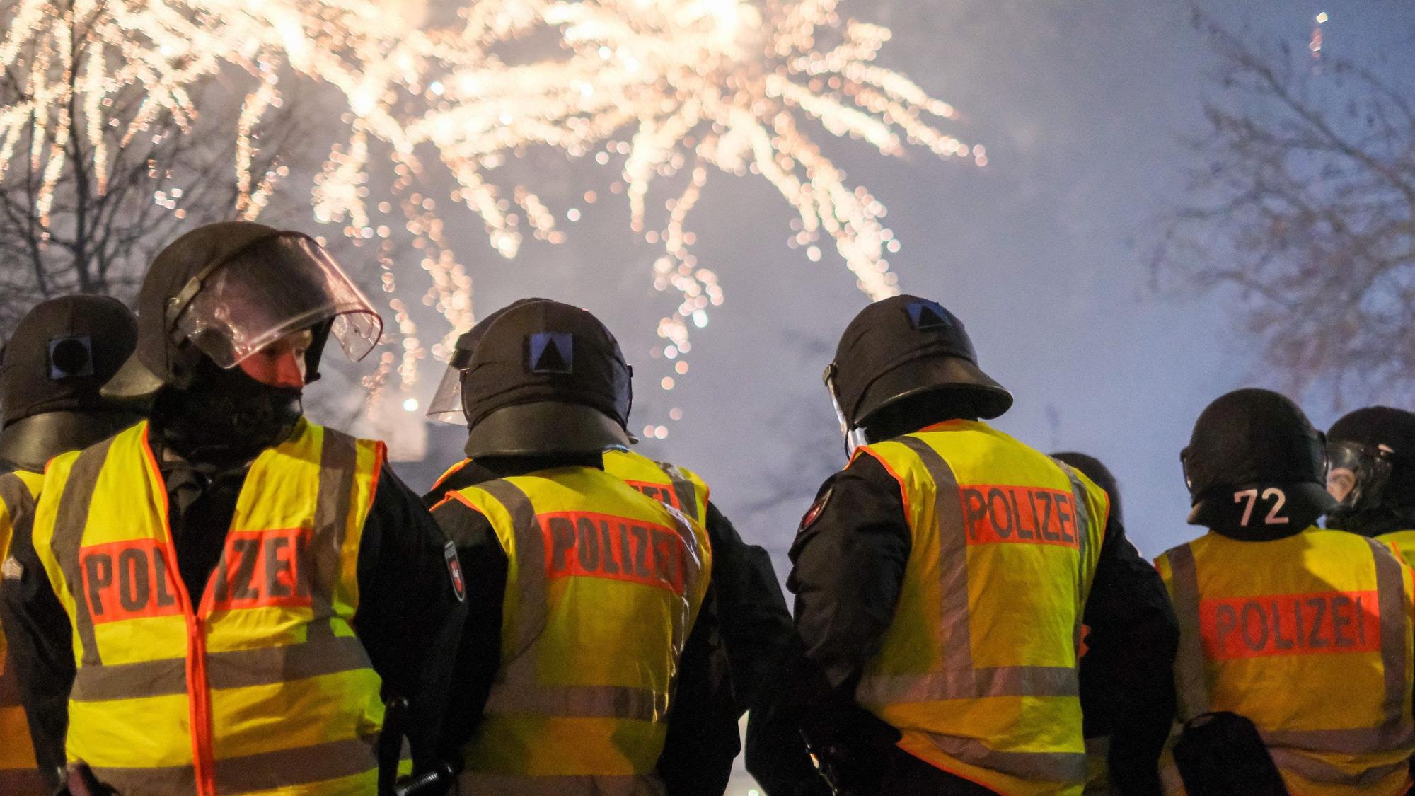 Polizeibeamte stehen in Hannover in der Innenstadt und beobachten ein Feuerwerk.