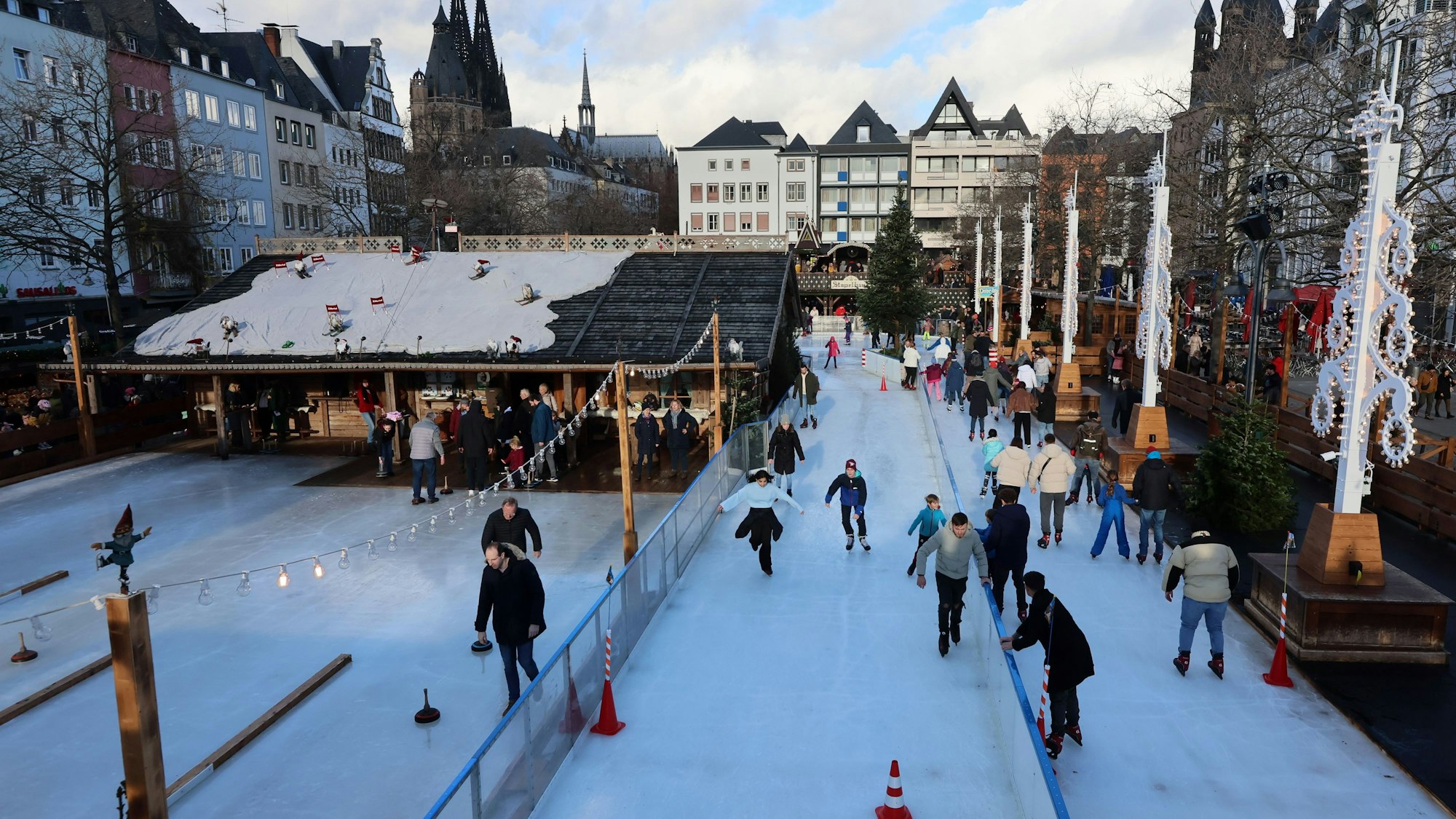 Der Weihnachtsmarkt auf dem Heumarkt mit Eisbahn und Eisstockschießen, im Hintergrund ist der Dom.
