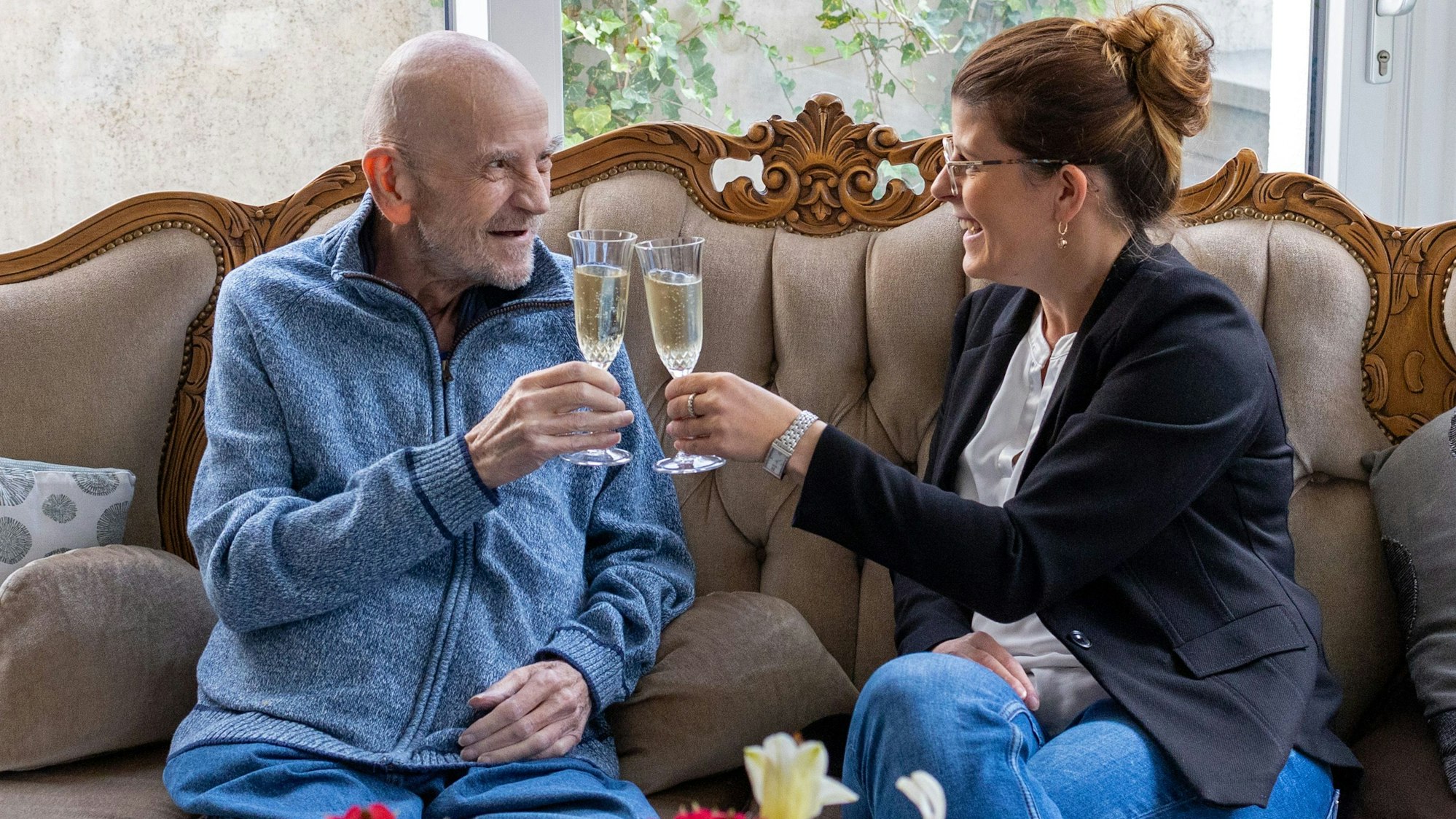 Das Foto zeigt einen Gast des Hospizes am Evangelischen Krankenhaus in Bergisch Gladbach, der ein Glas Sekt trinkt