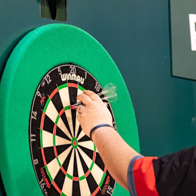 Ein Darts-Spieler zieht seine Pfeile aus der Dartscheibe