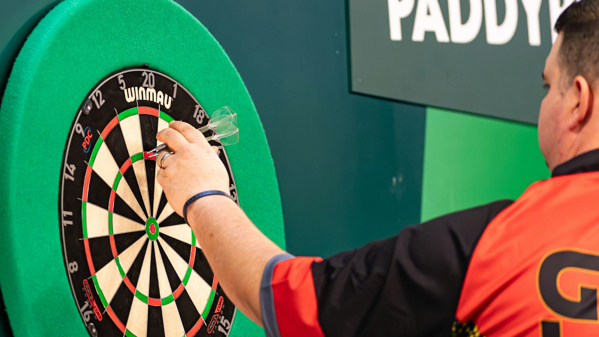 Ein Darts-Spieler zieht seine Pfeile aus der Dartscheibe