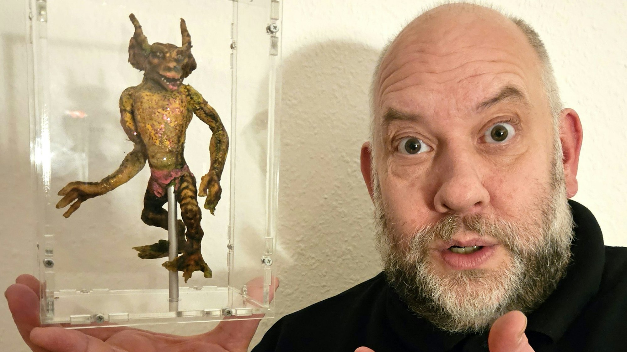 Puppenspieler und Sammler Gerd J. Pohl hält eine Glasbox mit seinem jüngsten und zugleich weltberühmten Zugang für seine Sammlung in Händen: eine Gremlin-Figur aus dem Kinofilm „Gremlins 2“.