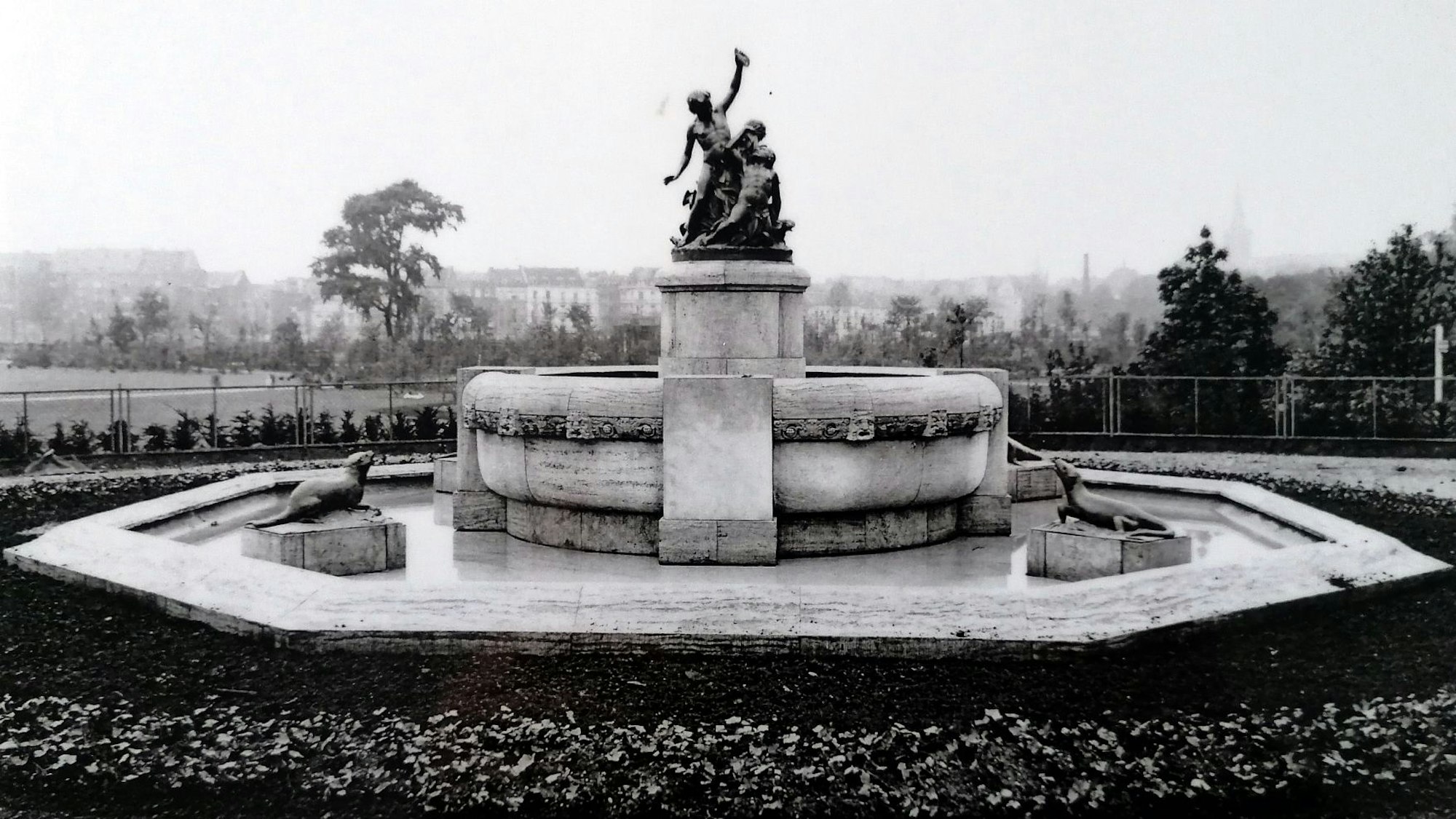 Das Schwarz-Weiß-Bild zeigt einen Brunnen mit Tierfiguren, die im großen Wasserbecken auf Podesten platziert sind.