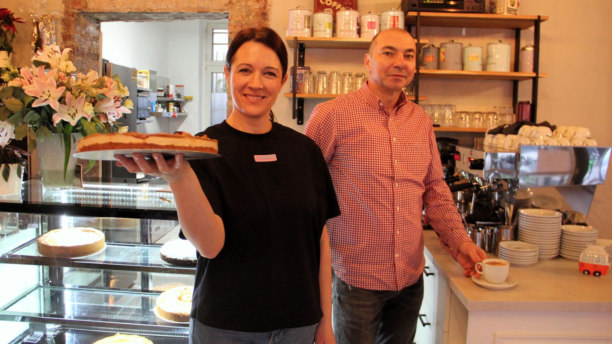 Zwei Menschen stehen mit Kuchen in der Hand am Buffet.