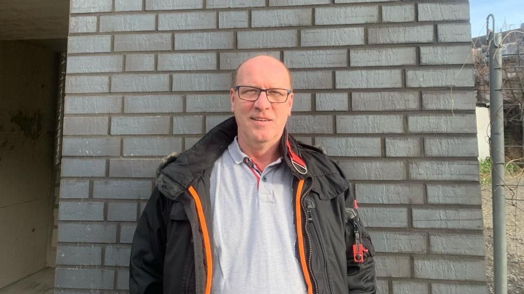 Michael Klein ist 1. Vorsitzender des 1. Dartteam Köln von 1998 e.V., steht vor einer geklinkerten Wand.